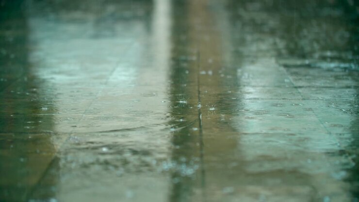 Rainfall drops and splashes hit the pavement tile path sidewalk