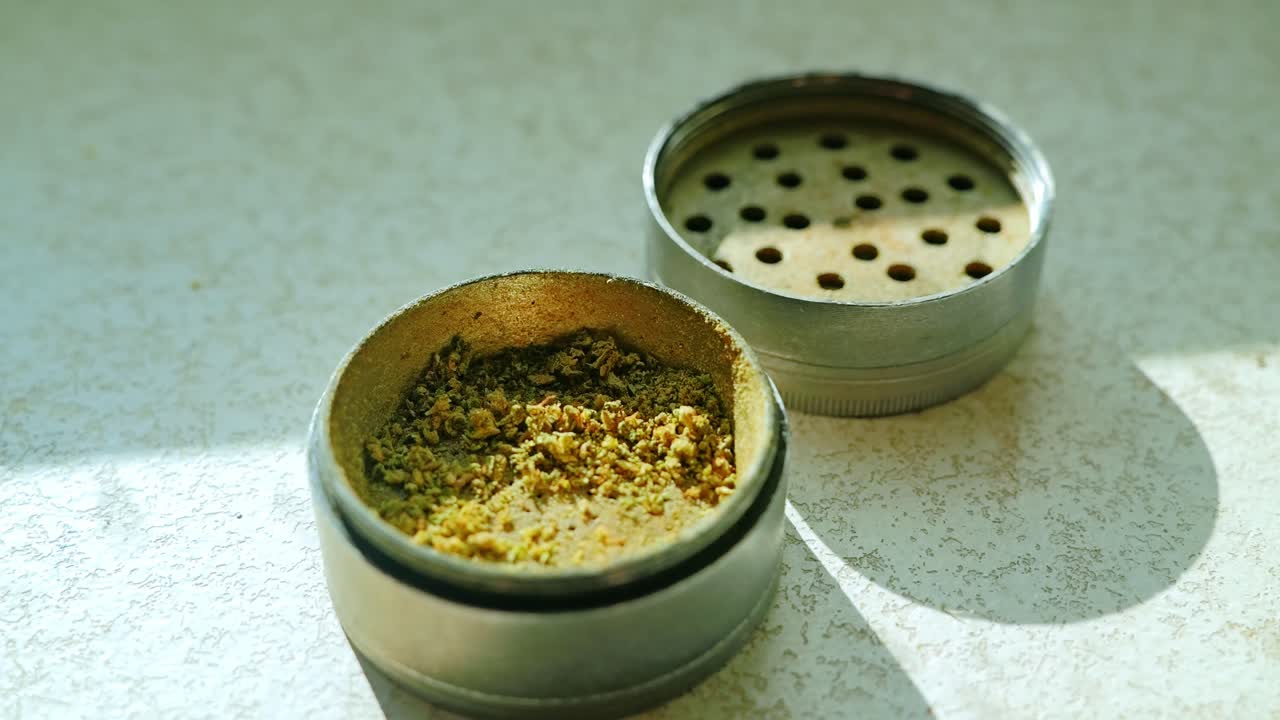 Open metallic grinder with cannabis pieces shows raw herbal texture in detail