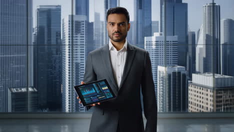 businessman holding a tablet with data analytics in a modern office