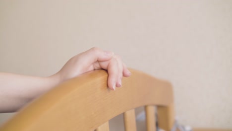 Mutter-Schaukelt-Mit-Der-Hand-Ihr-Babybett-An-Der-Beigefarbenen-Wand-Im-Kinderzimmer