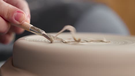 close-up of shaping process of workpiece with a tool in a pottery studio. clay shavings. slow motion