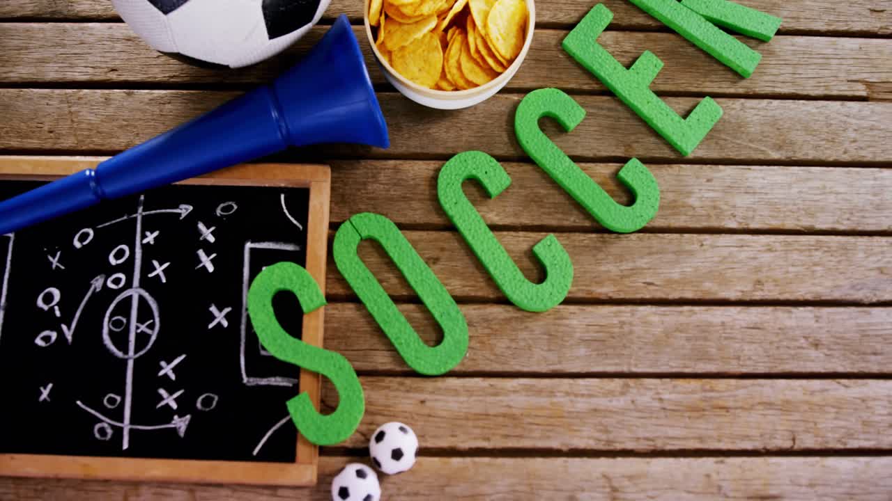 tazón de bocadillos, fútbol, cuerno y pizarra en una mesa de madera 4k