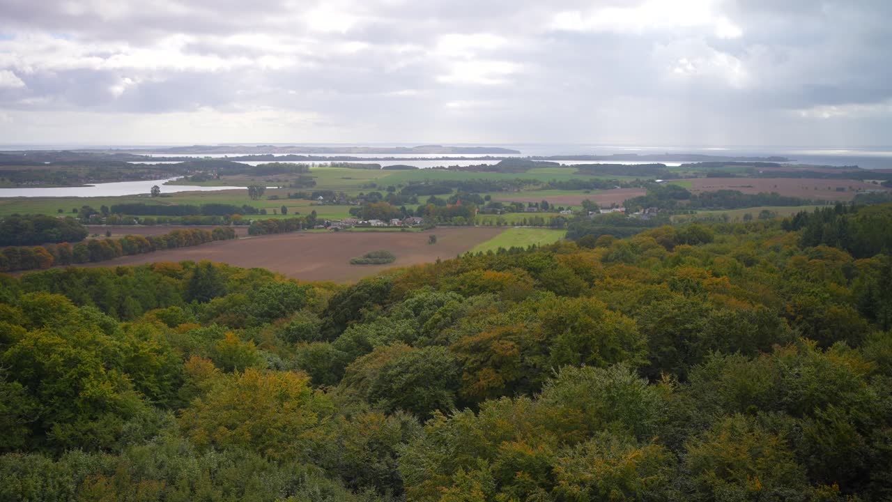 vista aérea de rügen, alemania, con el bosque en primer plano en un día nublado de finales del verano con campos y lagos en el fondo