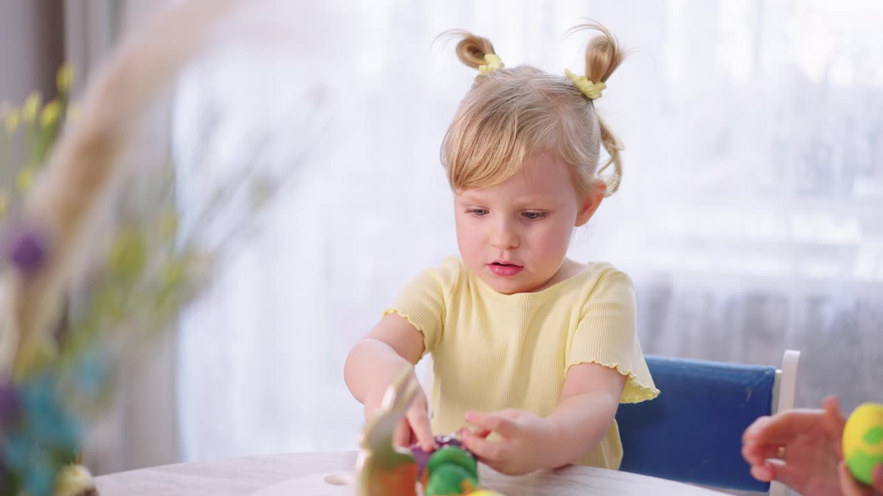 Simpatica bambina che decora uova di Pasqua colorate