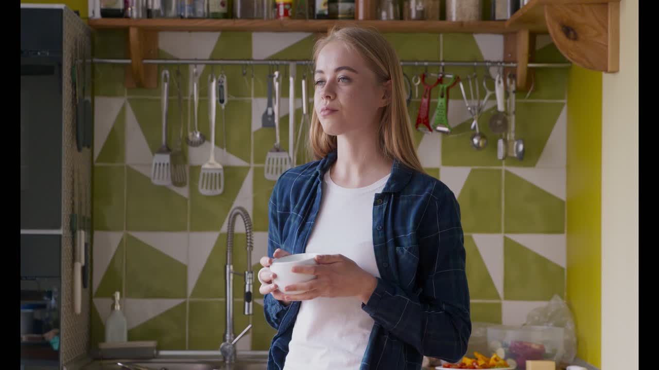 mujer disfrutando de una bebida en la cocina