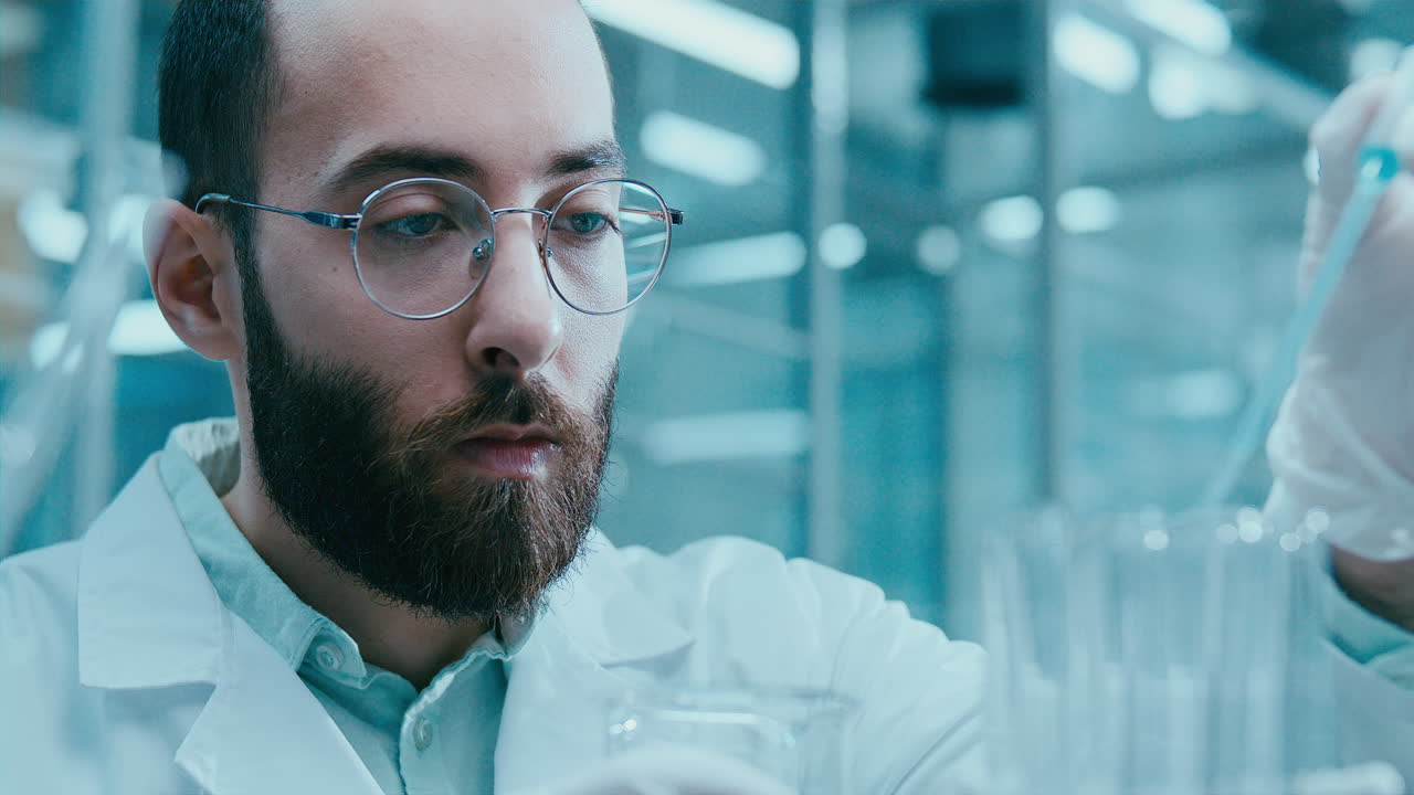Chimico che utilizza una pipetta per travasare liquido in provette in laboratorio