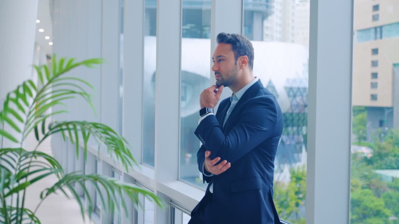 Man executive in deep thought leaning against an office windowsill ...