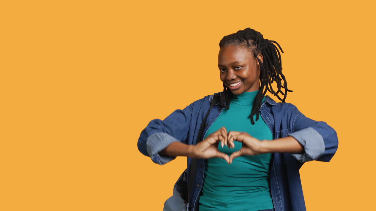 retrato de una mujer afectuosa y sonriente haciendo el símbolo del corazón, fondo del estudio
