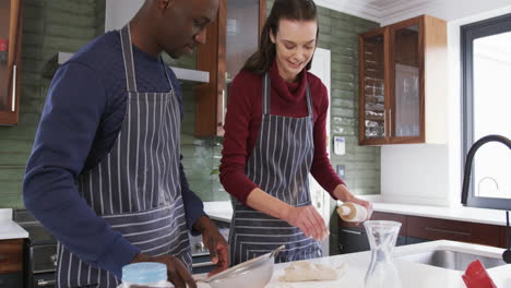 Feliz-Pareja-Diversa-Parada-En-La-Cocina,-Usando-Tableta-Y-Masa-Rodante,-Cámara-Lenta