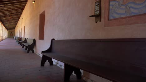 wooden benches line the adobe walls of a california mission