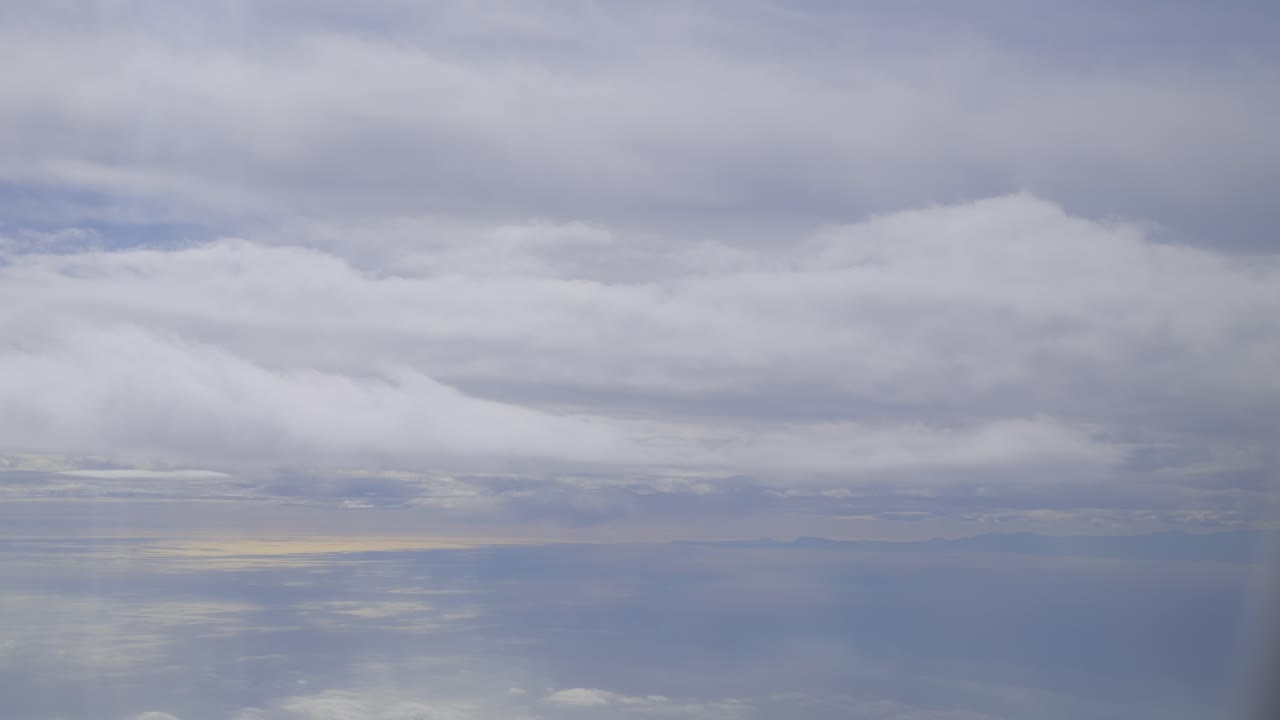 Cloudy sky over calm ocean with soft sunlight reflections, serene and peaceful view