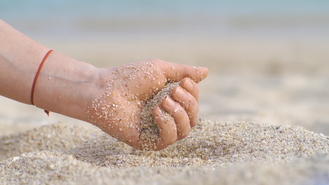 Sand falling from hand in slow motion on a beach. Vacation and travel concept. Shot on super slow motion camera 1000 fps.