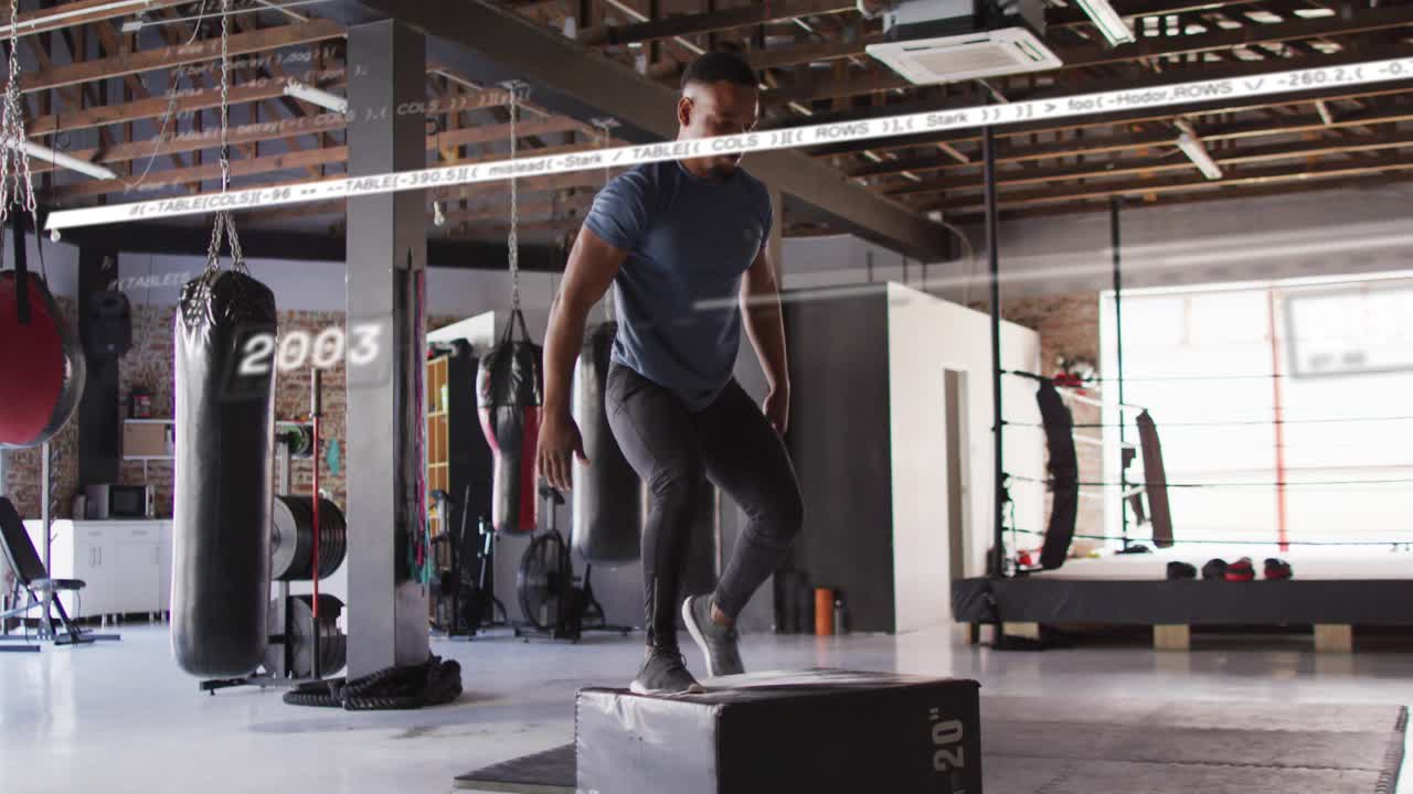Male athlete swinging arms, launching, landing on gym plyo box while year markers tracking fitness