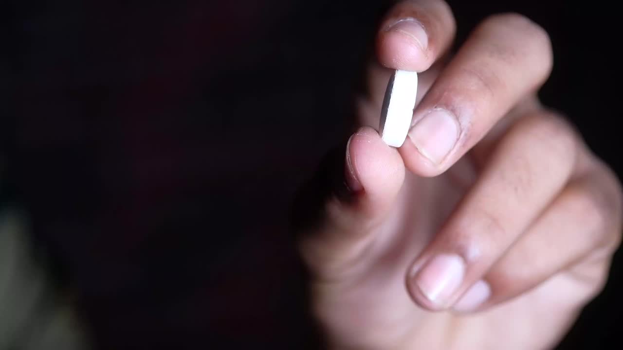 mano con una píldora blanca