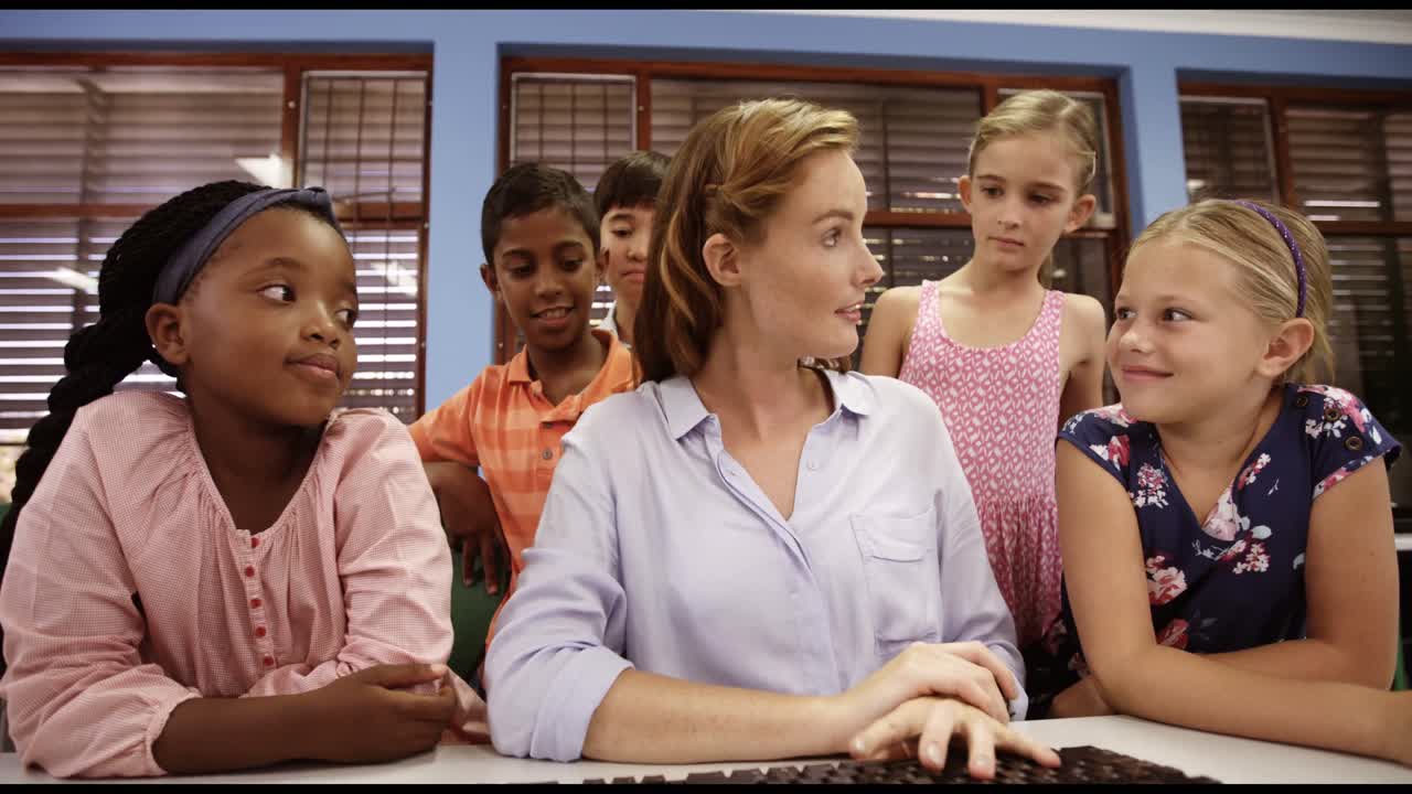 Teacher assisting school kids on personal computer in classroom