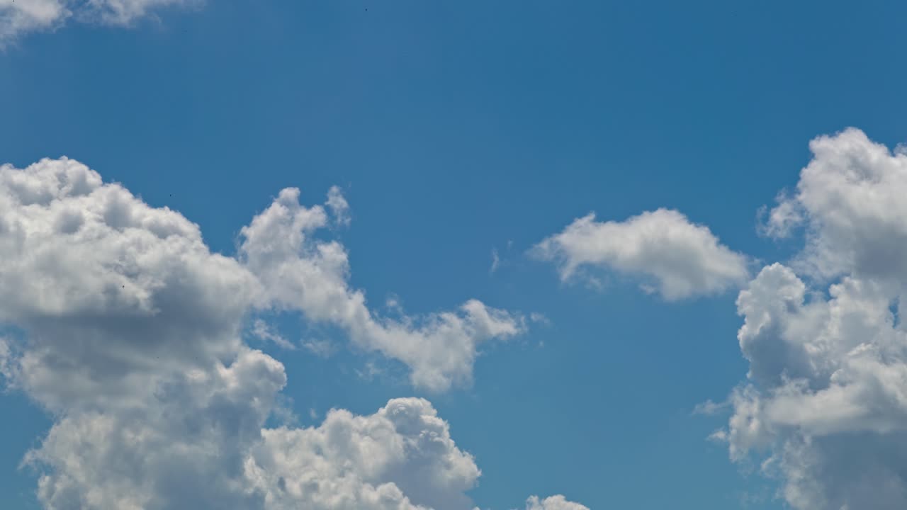 Clouds float in the blue sky above during midday