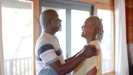 Happy-senior-african-american-couple-embracing-and-kissing-in-kitchen,-slow-motion