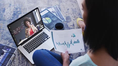 African-american-woman-holding-a-document-having-a-video-call-on-laptop-at-home