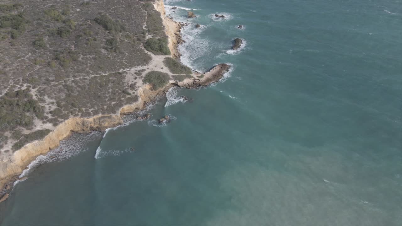 olas espumosas del mar salpicando en la costa rocosa a la luz del sol