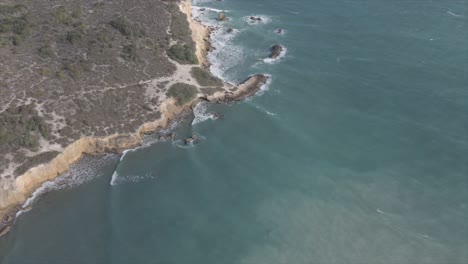 olas espumosas del mar salpicando en la costa rocosa a la luz del sol