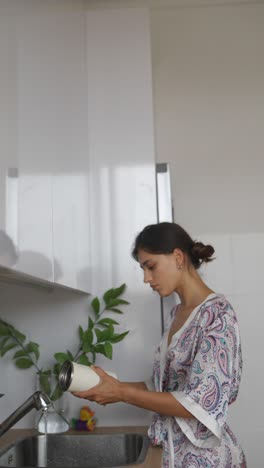 woman washing a water bottle in the kitchen