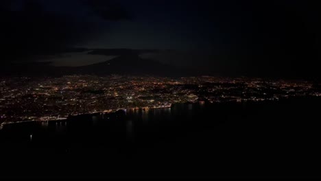 night view of catania city, in sicilia taken at 1000m high from a plane cockpit, with the shape of the etna volcano at the back