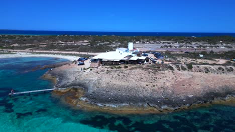 sailboats anchored in turquoise waters near a beach restaurant on the idyllic island formentera, spain. great aerial view flight tilt up drone