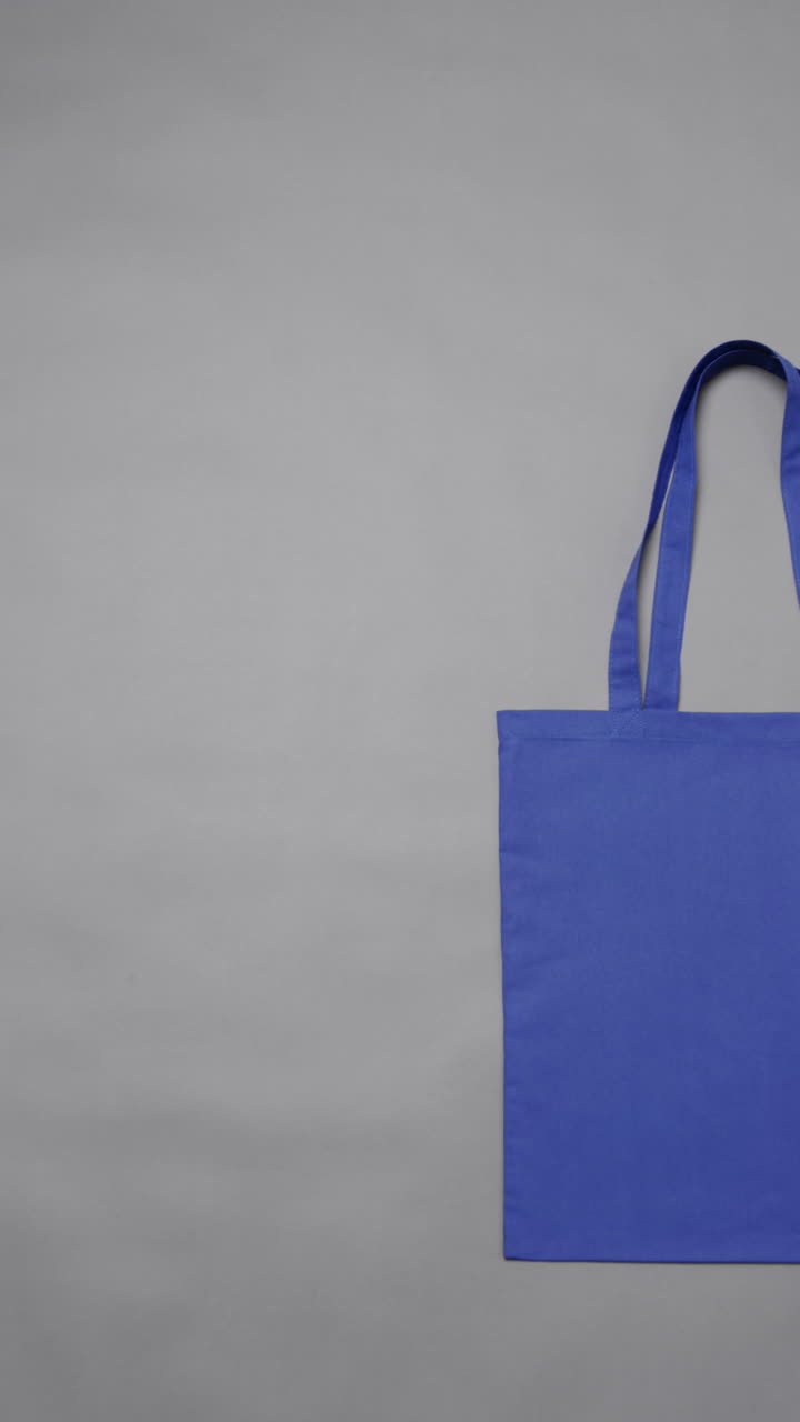 Vertical video of high angle view of blue canvas bag with copy space on white background