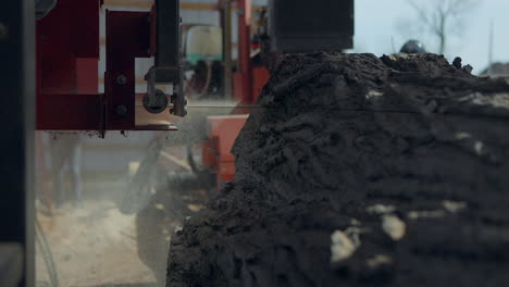 Low-angle-of-a-saw-blade-at-a-sawmill-cutting-through-a-tree-trunk