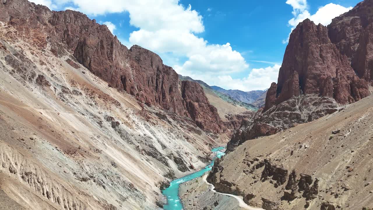 Aerial drone shot showcasing clear blue river waters winding near a remote hillside monastery.