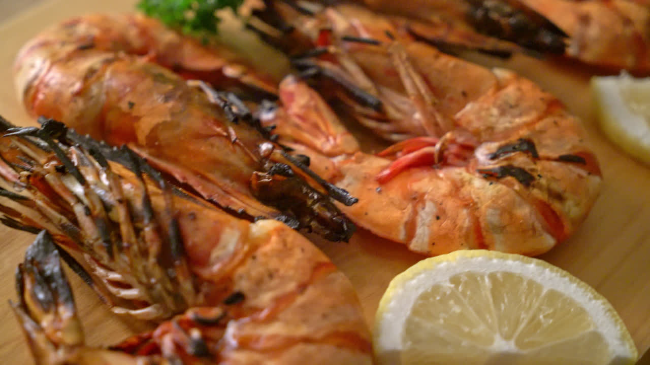grilled tiger prawns or shrimps with lemon on wood board