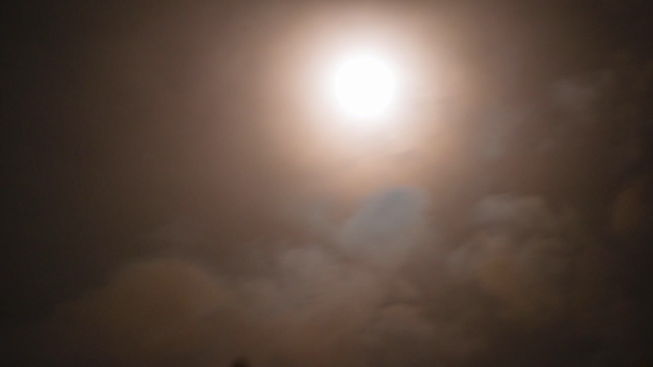 Brightly Lit Full Moon Timelapse Moving Out of Frame in Sky with Thick Clouds Swiftly Passing on Stormy Night