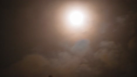 brightly lit full moon timelapse moving out of frame in sky with thick clouds swiftly passing on stormy night