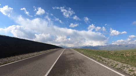 point of view driving a car on a road. mount elbrus is visible in the background.