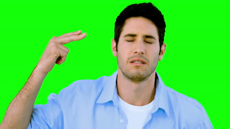 man pretending to shoot himself with hand on green screen