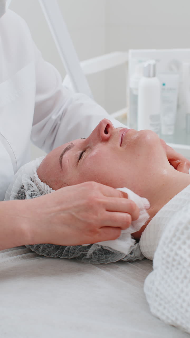 cosmetólogo médico limpia la cara y el cuello de la mujer procedimiento de limpieza con toallitas de algodón en la clínica de belleza