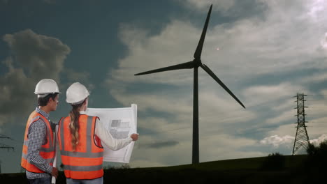 animation of wind turbine turning, male and female engineers reading plans with countryside