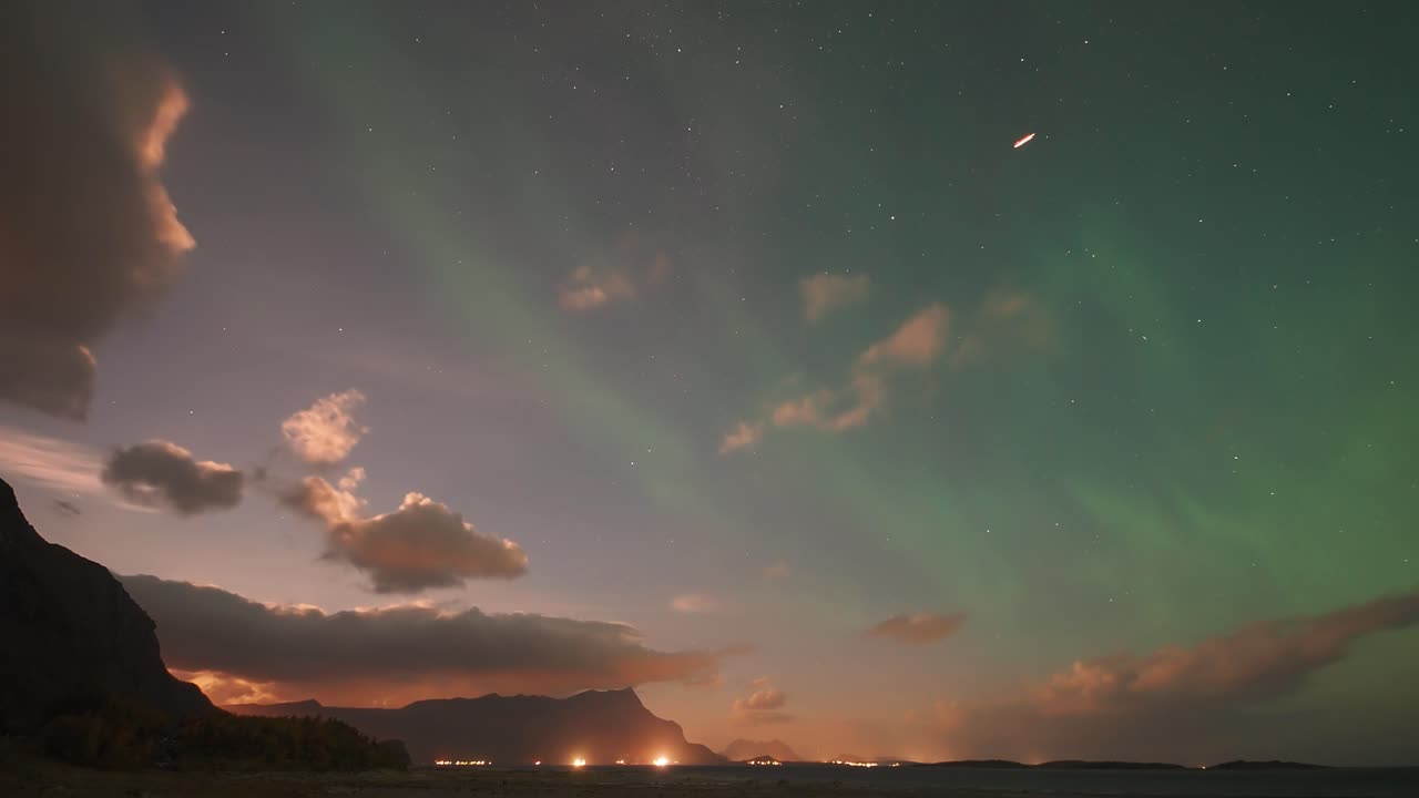 sea testigo de la hipnotizante danza de la aurora boreal mientras ilumina las nubes contra el telón de fondo de un vibrante atardecer, creando un espectáculo celeste impresionante.