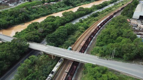 train crossing under a concrete bridge with cars