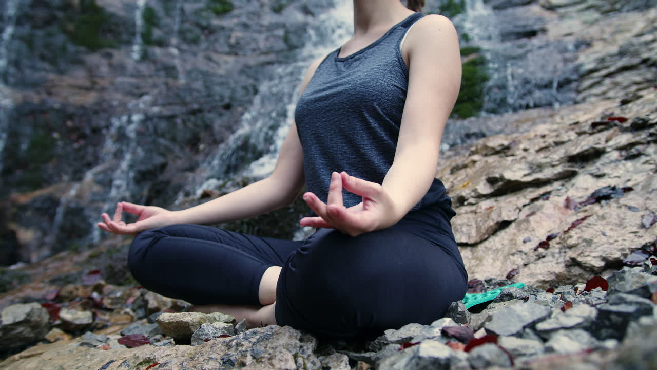 meditación en la naturaleza, una chica relajándose en una postura de yoga cerca de una cascada, de mano