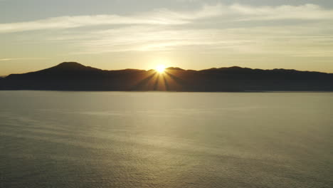 beautiful aerial drone view sunset over the ocean and mountains on the horizon