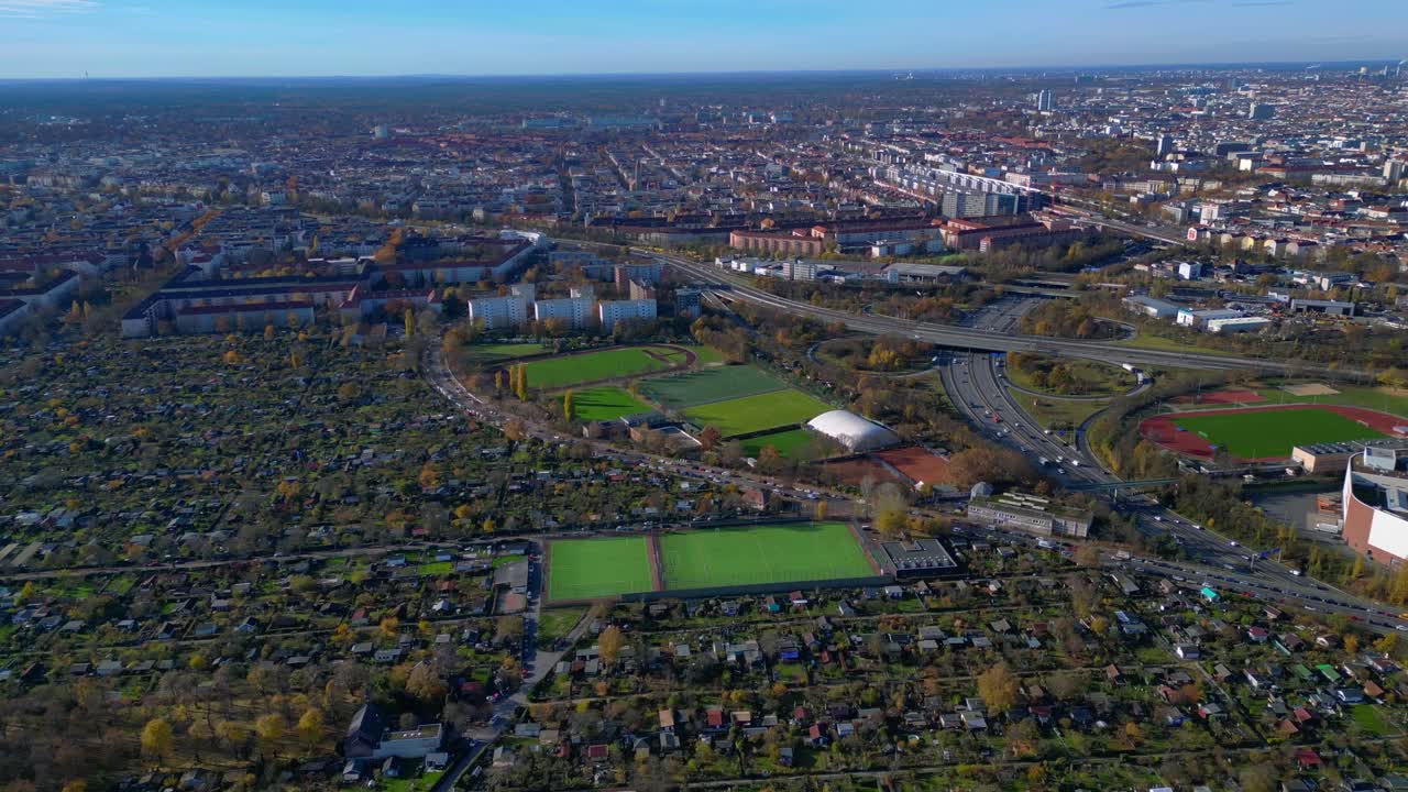 Berlin urban landscape with a large allotment garden area, sports soccer fields, football pitches and city infrastructure. Magic aerial view flight panorama orbit drone