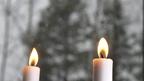 cerca de dos velas encendidas en la ventana con clima invernal afuera