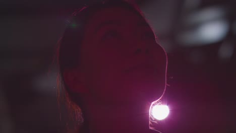 close up of woman visiting and interacting with immersive art exhibition backlit by light from projector 8