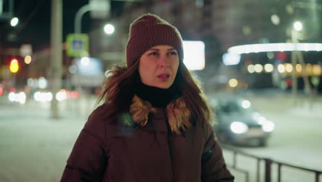 vista en primera persona de una mujer con un abrigo de invierno con una capucha de piel, caminando por la noche en un entorno urbano con luces borrosas de la ciudad y coches en el fondo