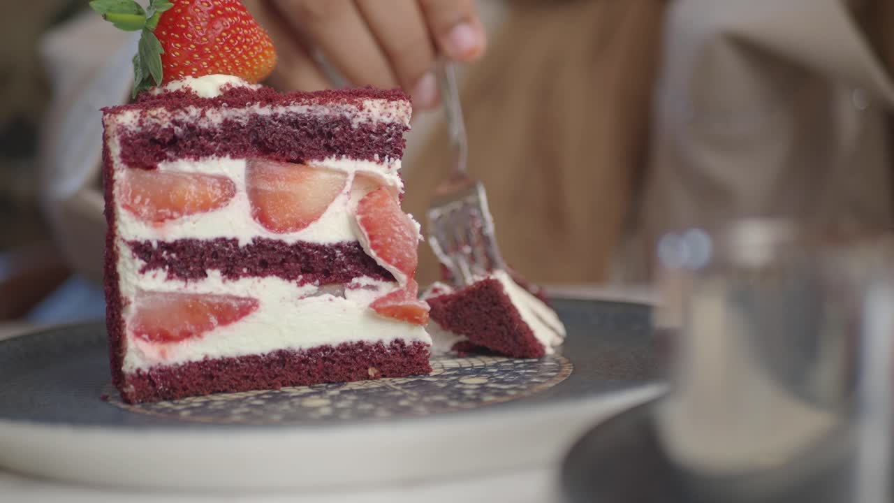 persona comiendo una rebanada de pastel de fresa de terciopelo rojo