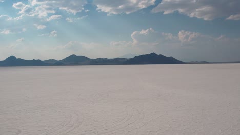 Bonneville-Salt-Flats-in-Utah-United-States,-Vast-Wild-White-Land-Ground-Covered-With-Salt-and-Minerals,-Visitors-Tourists-Walking-in-Desert-Natural-Formation-With-Mountains-in-Horizon