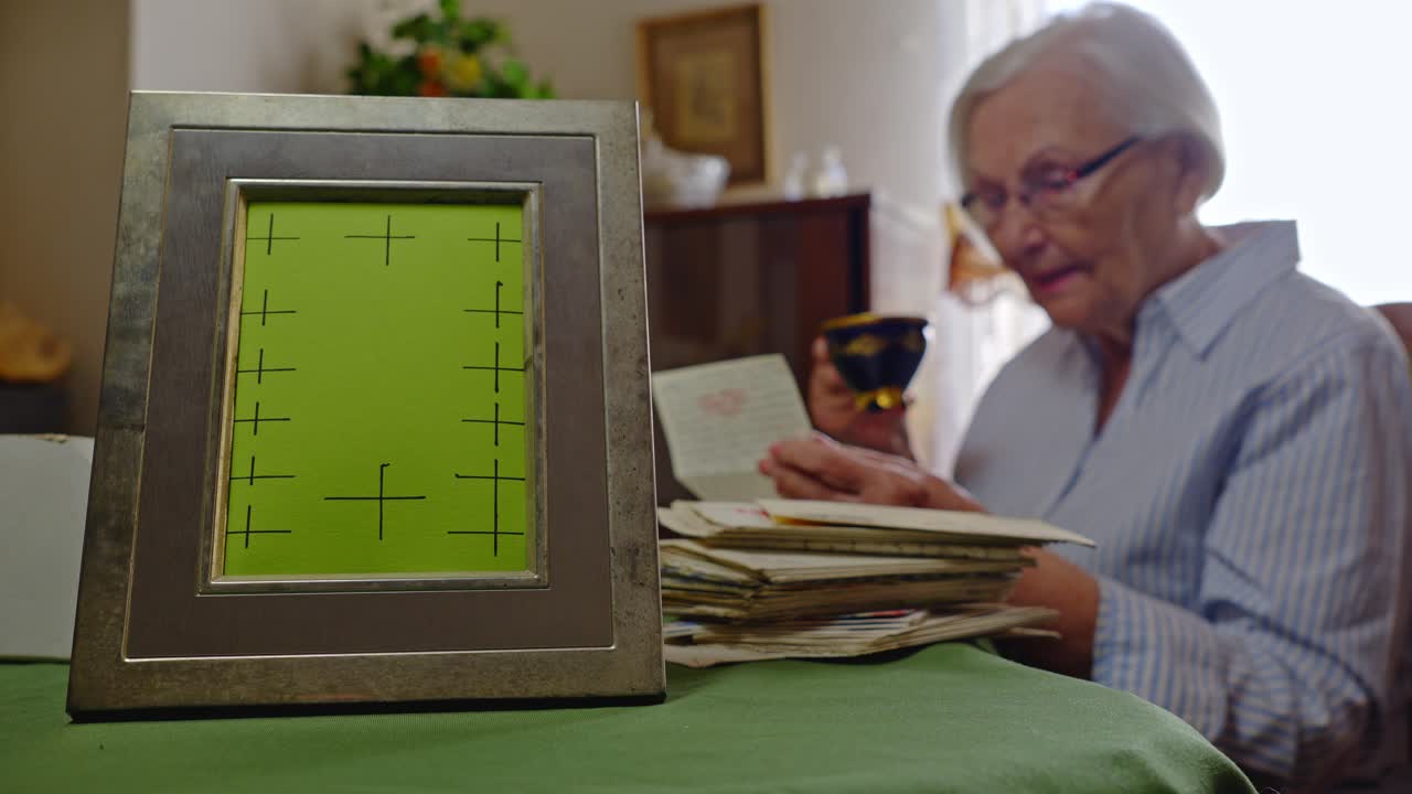 Elderly Mum reading old letters with blank mockup family photo frame