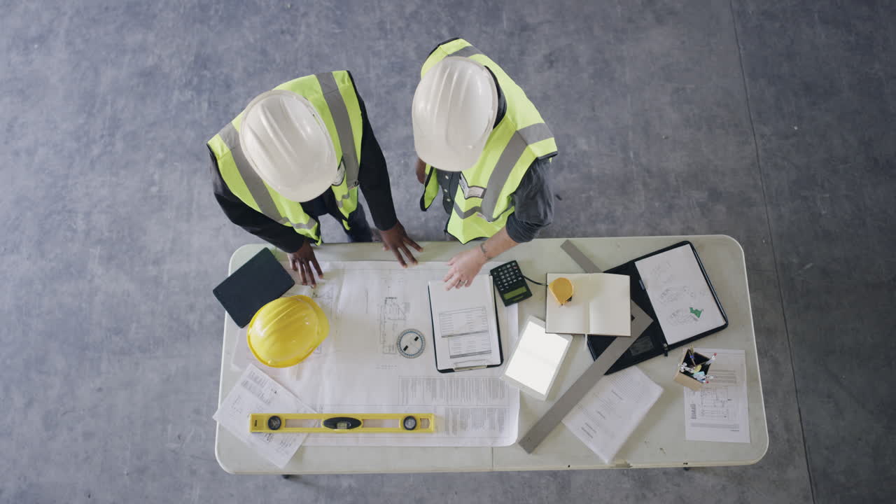 trabajadores de la construcción que revisan los planes