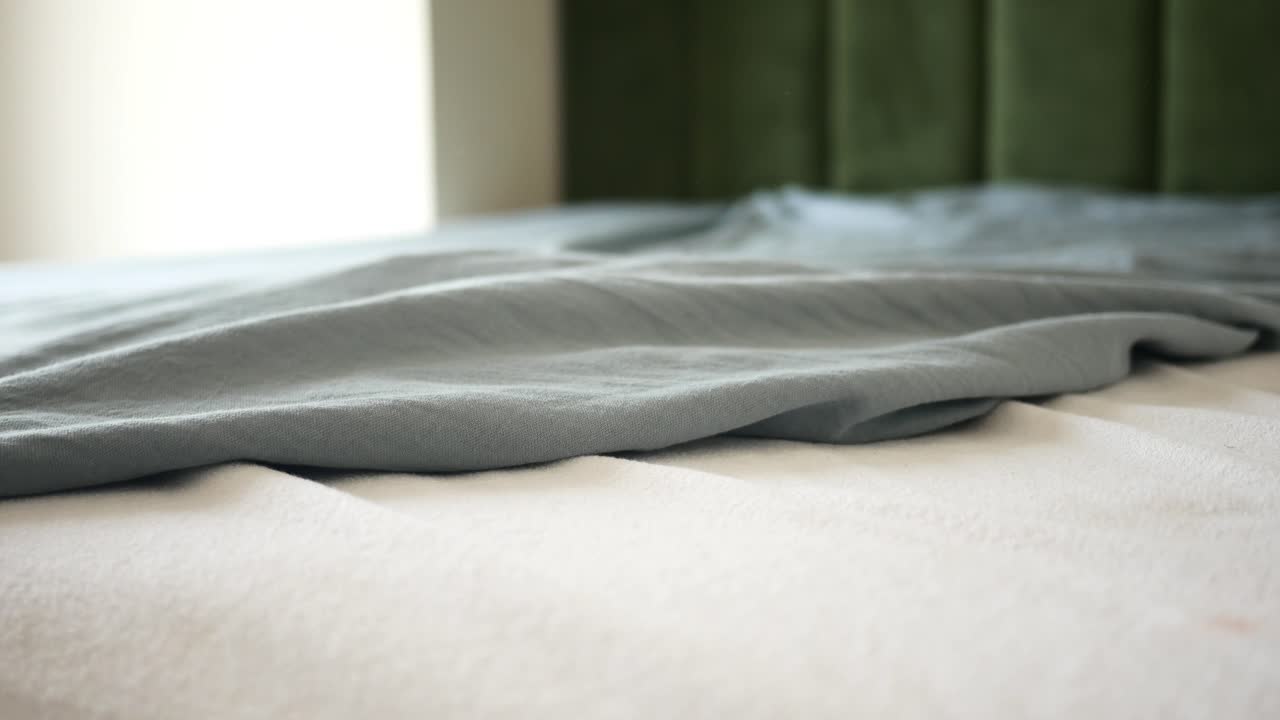 una manta gris doblada en una cama blanca